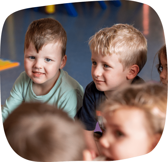 Children sitting together and smiling indoors.